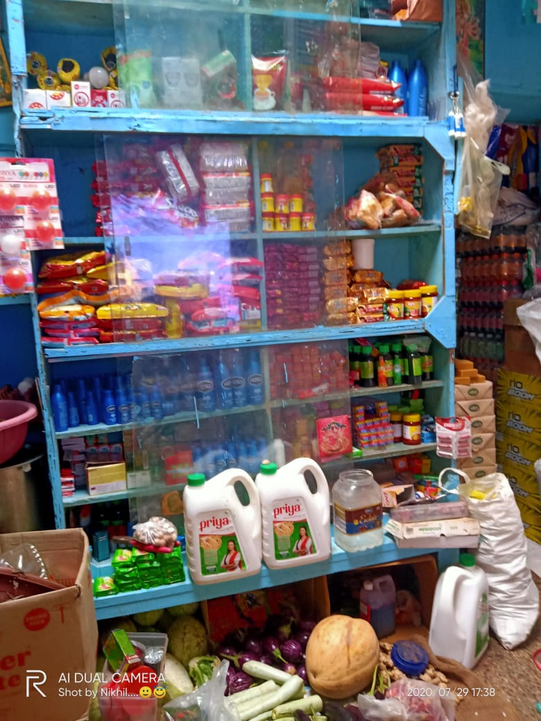 Bright interior view of store shelves stocked with packaged groceries and household goods in a neighborhood kirana shop